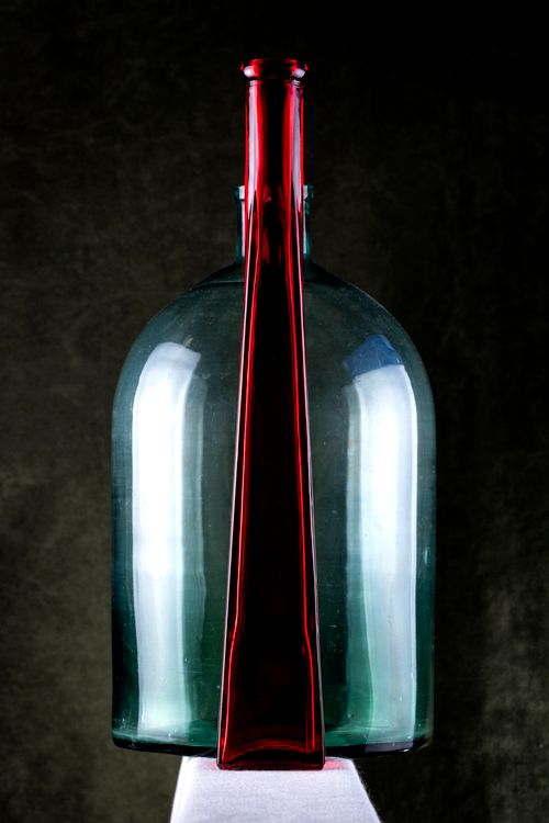 Free A striking visual of a red bottle artistically aligned with a blue glass bottle against a dark background. Stock Photo