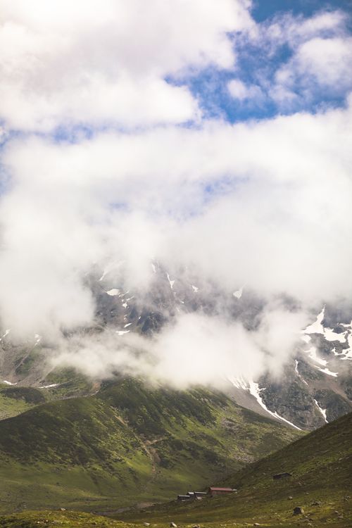 Free Majestic mountain peaks partially hidden by clouds create a mystical landscape scene. Stock Photo