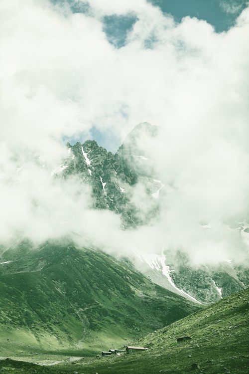 Free Ethereal view of a mist-covered mountain summit with lush greenery at the base. Stock Photo