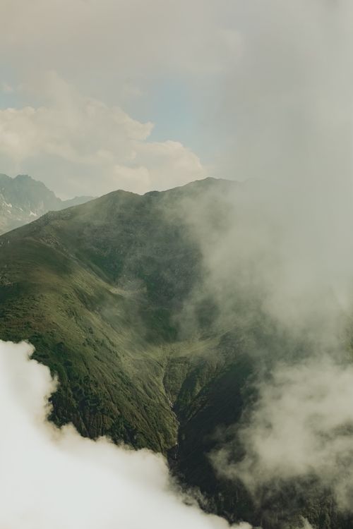 Free A breathtaking aerial view of a mist-covered mountain valley with lush greenery, creating a serene atmosphere. Stock Photo