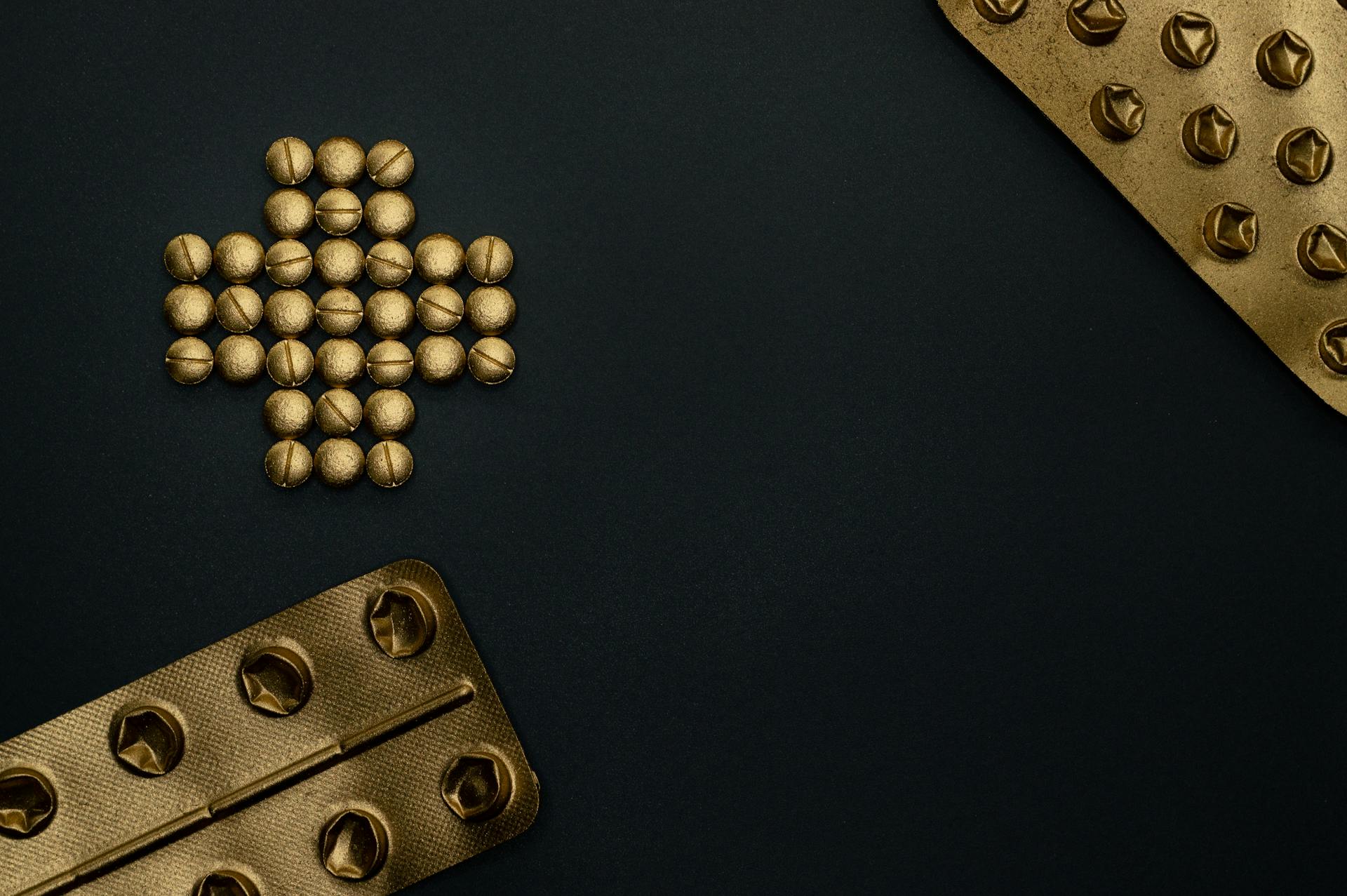 Artistic representation of golden pills and blister packs on a dark background, perfect for medical themes.