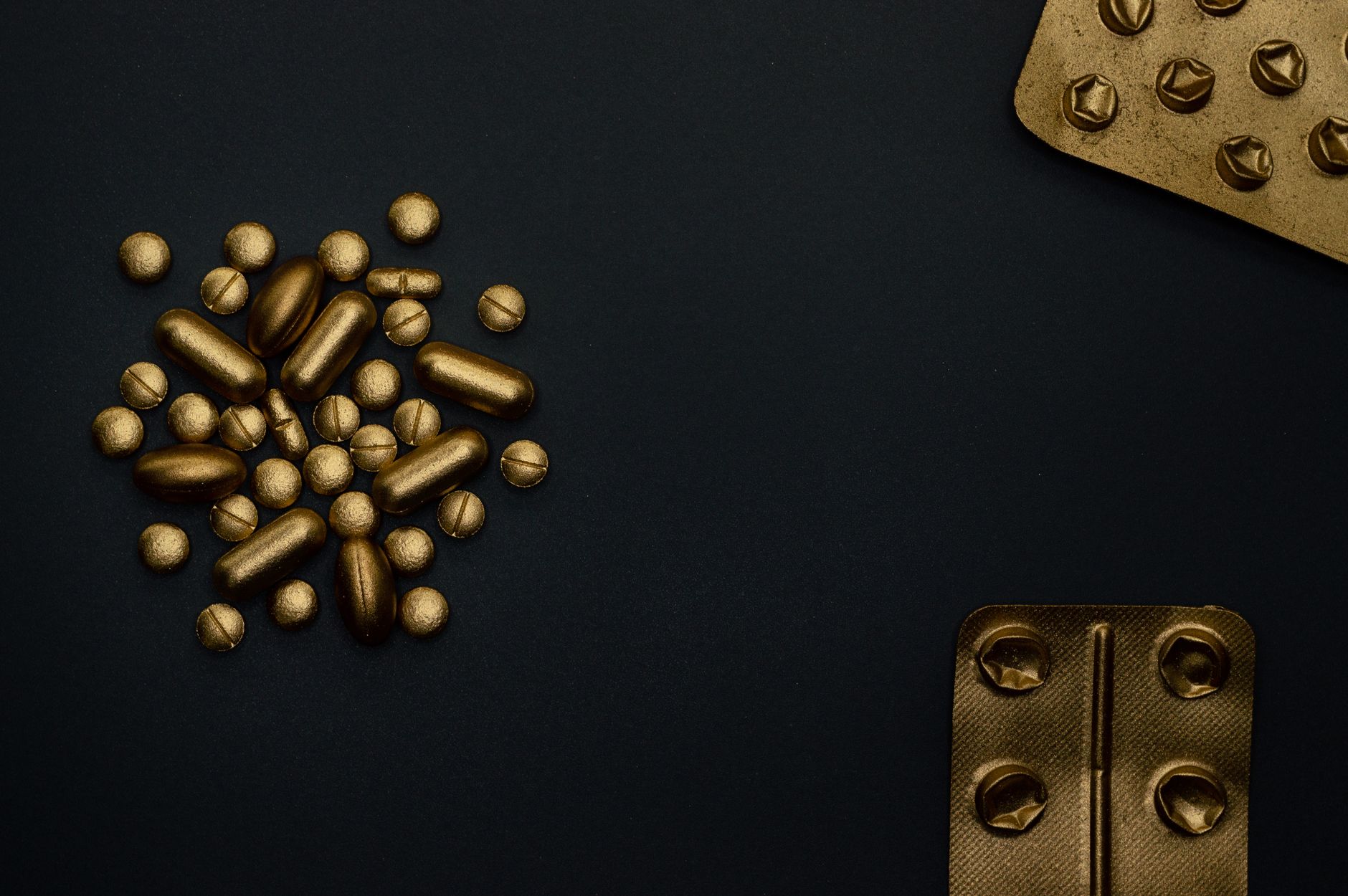 A conceptual image of golden pills and blisters on a dark background, symbolizing modern medicine.