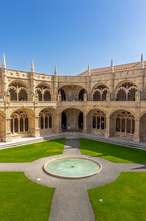 Free The intricate cloisters of Jerónimos Monastery in Lisbon, Portugal, display stunning Gothic architecture and lush gardens. Stock Photo
