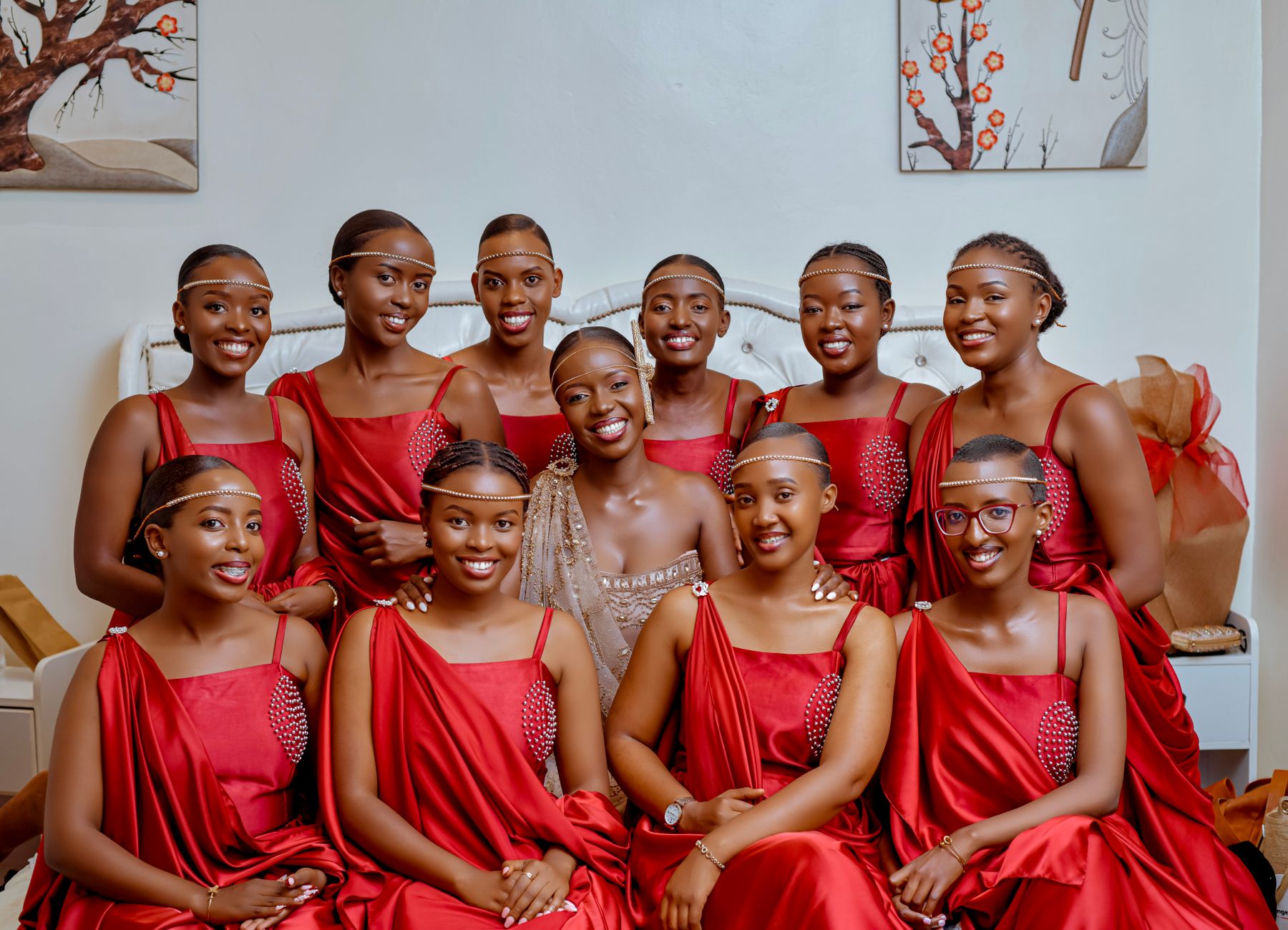 A joyful bridal party posing indoors in red dresses, showcasing elegance and happiness.