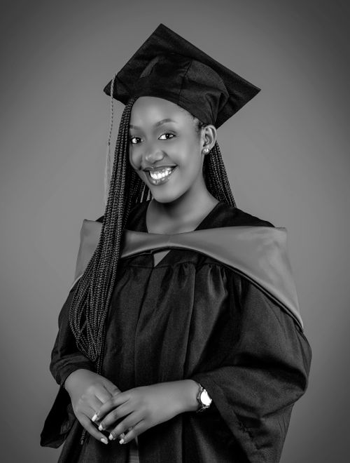 Free A black and white portrait of a smiling graduate in cap and gown, conveying achievement and joy. Stock Photo
