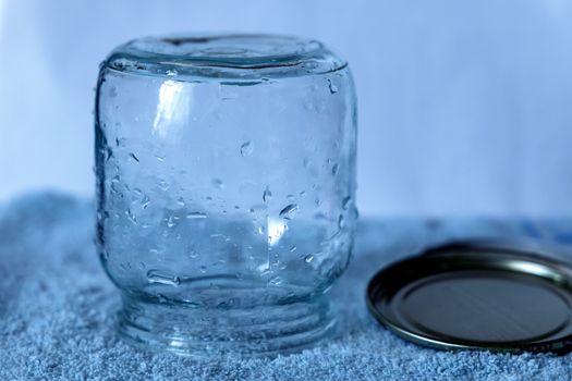 A transparent glass jar with a metal lid placed on a textured blue towel.