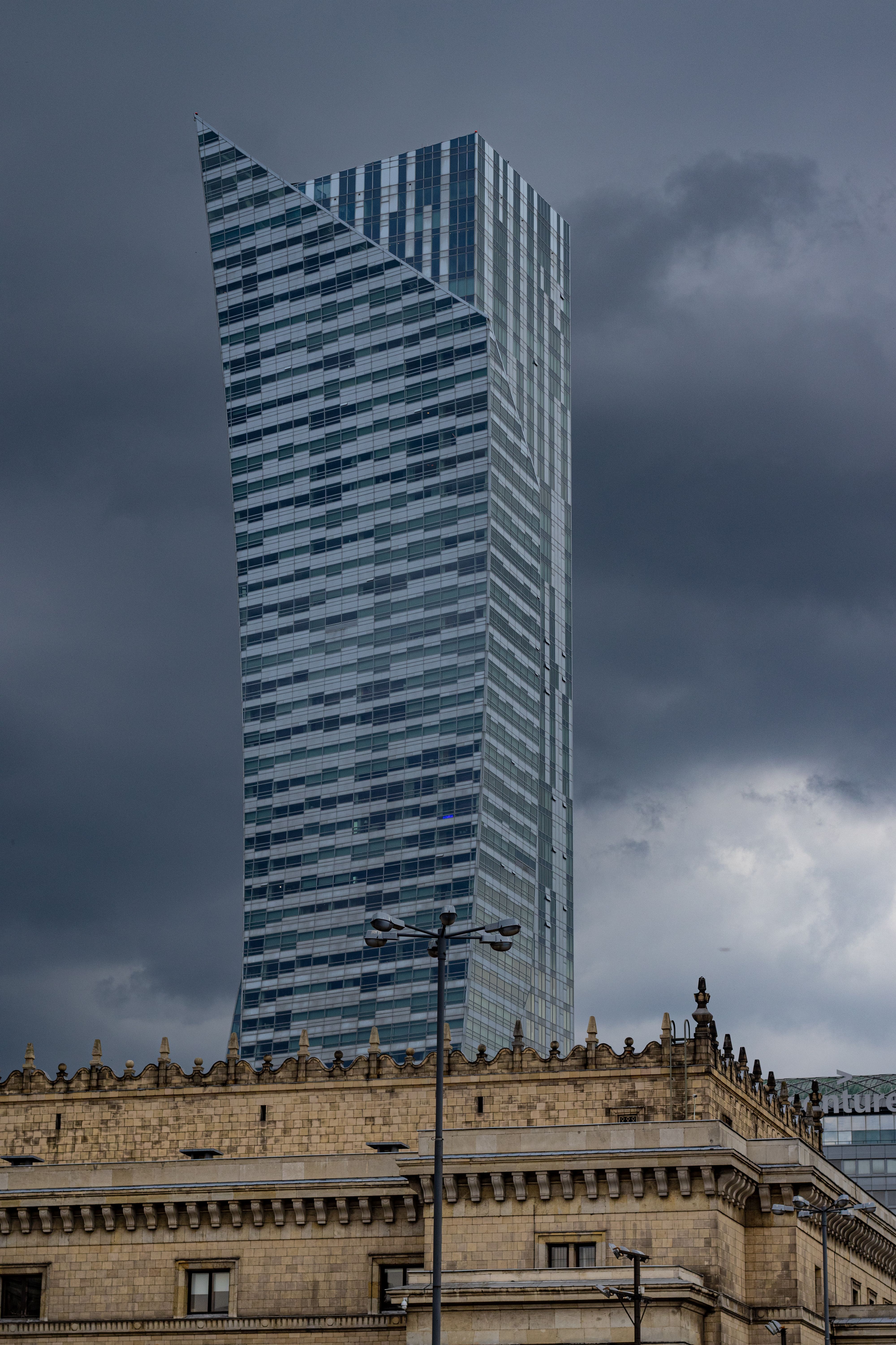 Złota 44 skyscraper stands tall in Warsaw with a stormy sky backdrop.