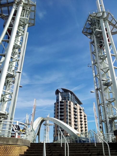 Tall building and structure under a clear sky in Manchester.