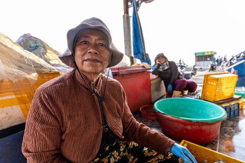 Free Portrait of a woman at an outdoor fish market, showcasing the vibrant life of local vendors. Stock Photo