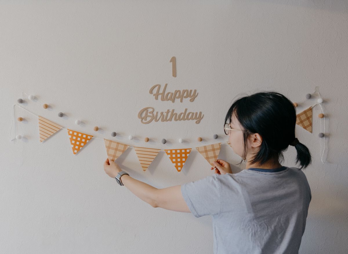Decorating a wall with a birthday banner for a first birthday