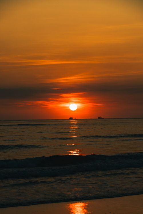 Free Sunset over the ocean in Quảng Trị, Vietnam. Calm waters reflect vibrant colors. Stock Photo