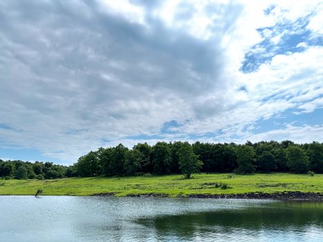 Serene summer scene of lush greenery and blue skies reflecting in a calm lake.