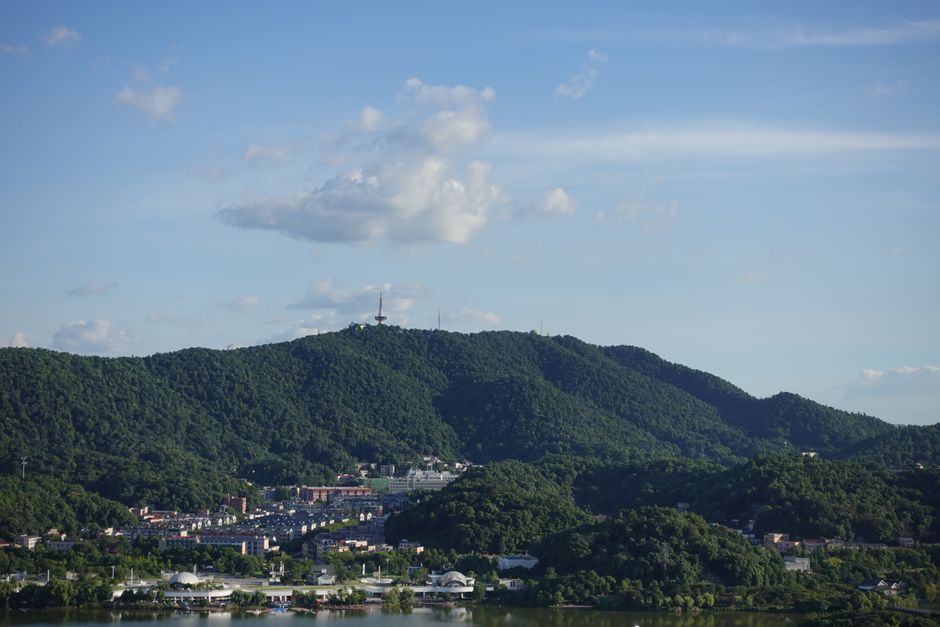 Breathtaking view of lush green mountains with a vibrant cityscape beneath, under a clear blue sky.