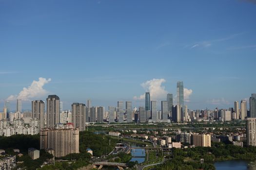 A stunning aerial view of a modern city skyline under a clear blue sky with scattered clouds., free online jigsaw puzzle on JigsawPuzzlesFreeOnline.org