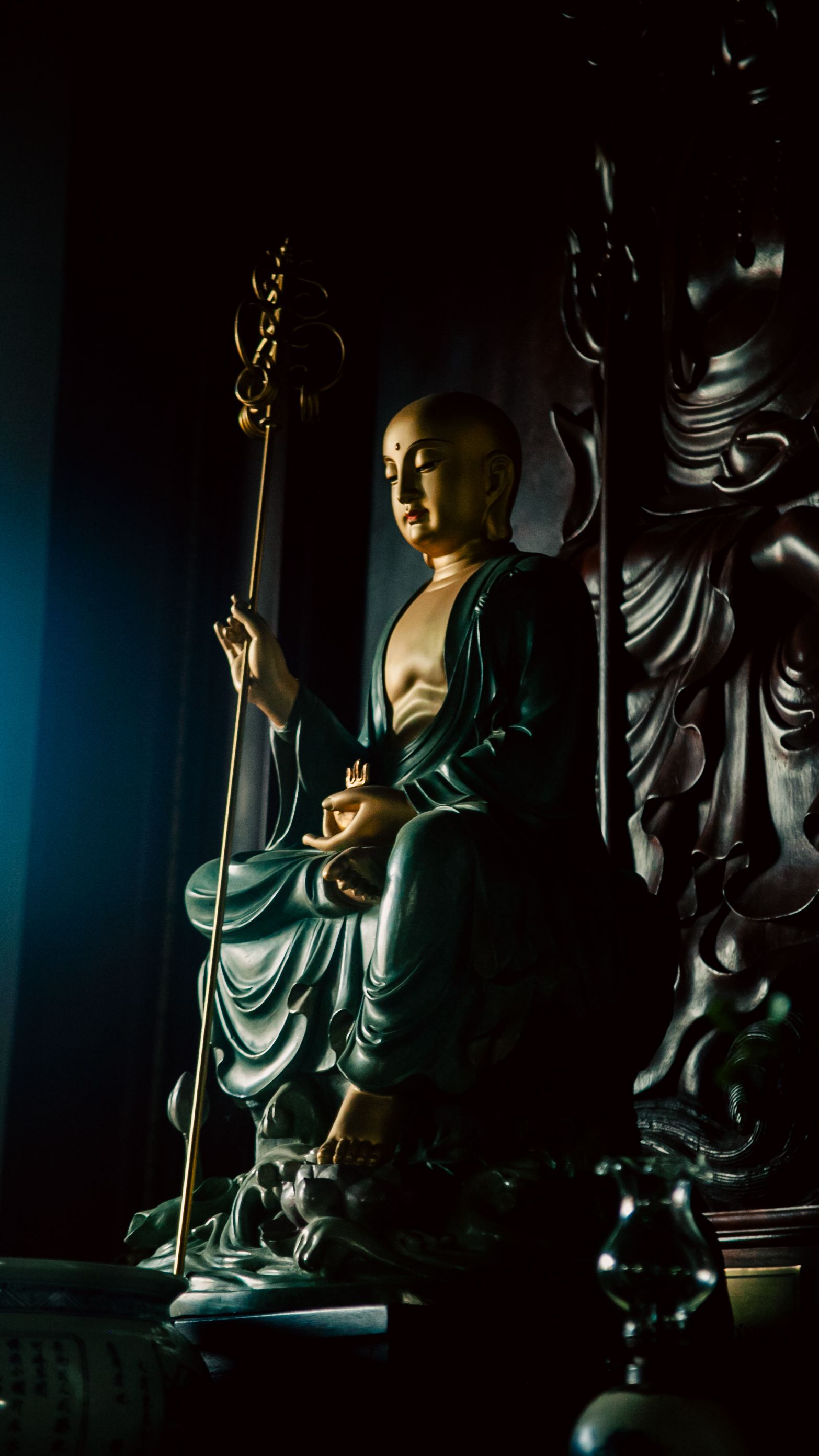 A serene Buddhist monk statue captured in low light, showcasing intricate details and meditative ambiance.