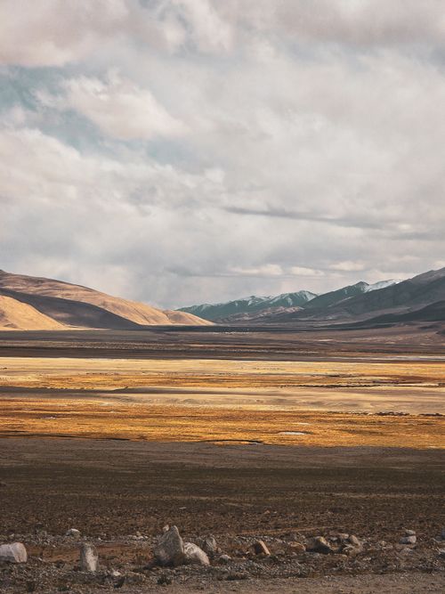 Free Breathtaking view of Ladakh's golden plains with mountains and dramatic skies. Stock Photo