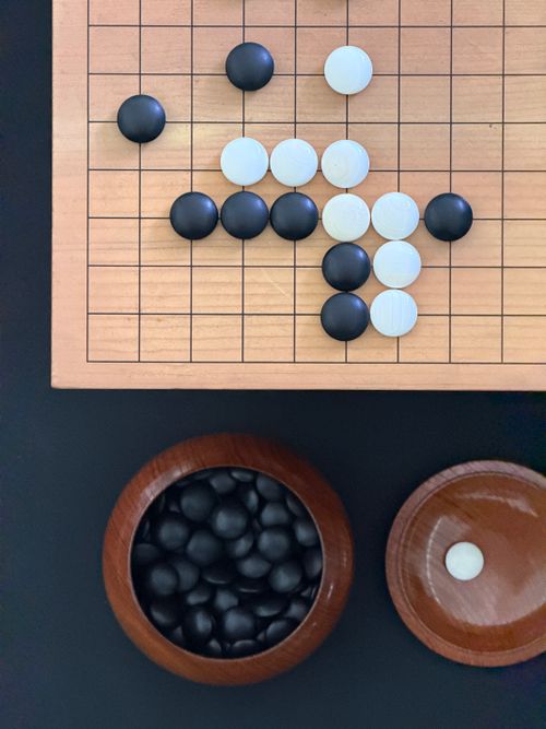 Free A strategic setup of a Go board game with black and white stones in wooden bowls. Stock Photo