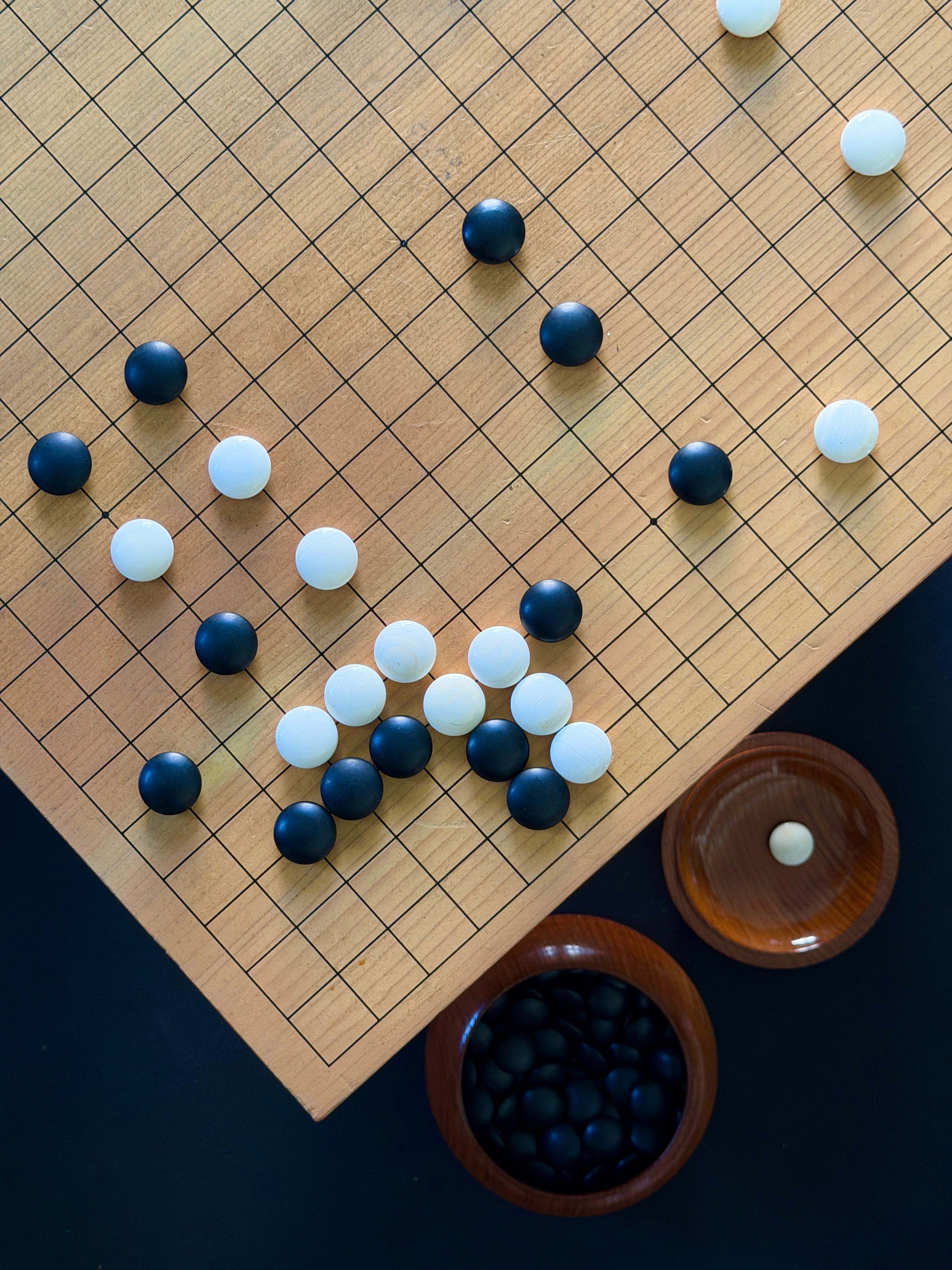 Aerial view of a Go board with black and white stones showcasing a strategic setup.