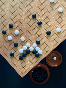 Aerial view of a Go board with black and white stones showcasing a strategic setup.