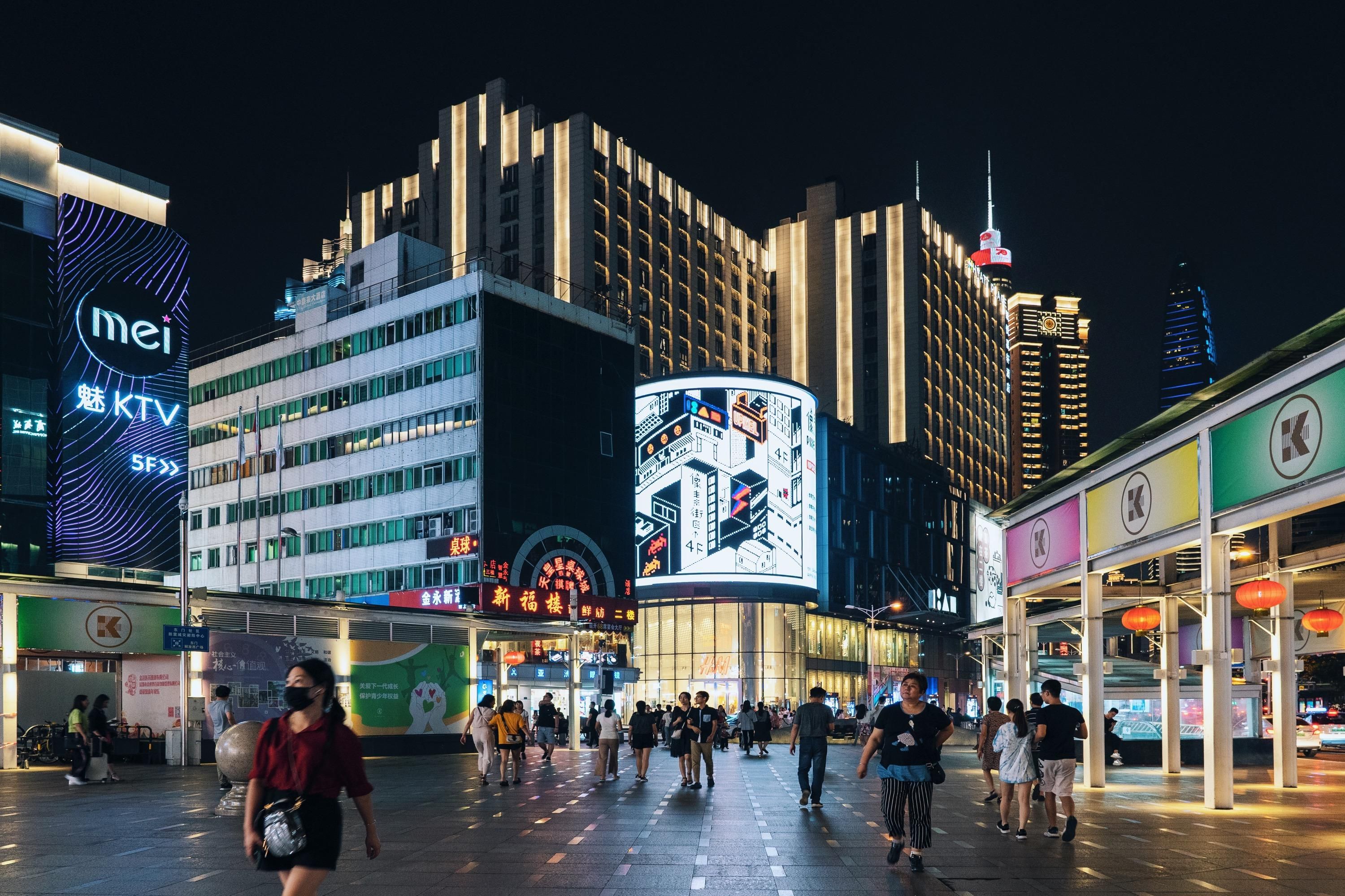 Illuminated city storefronts and digital signage in a busy shopping district at night
