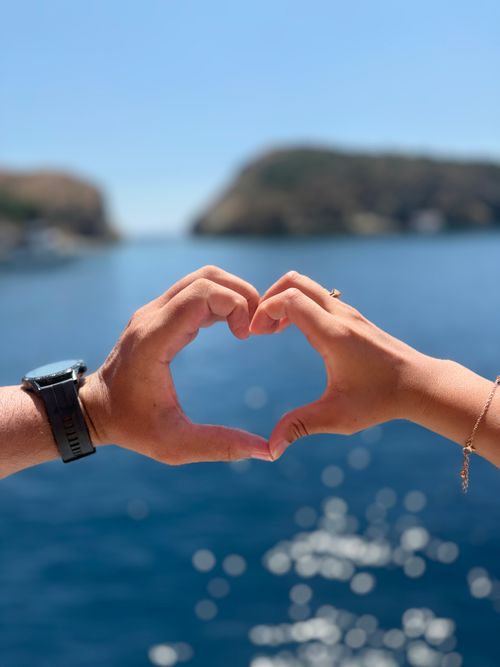 Free Romantic gesture by couple forming heart shape with hands overlooking ocean at Fethiye, Türkiye. Stock Photo