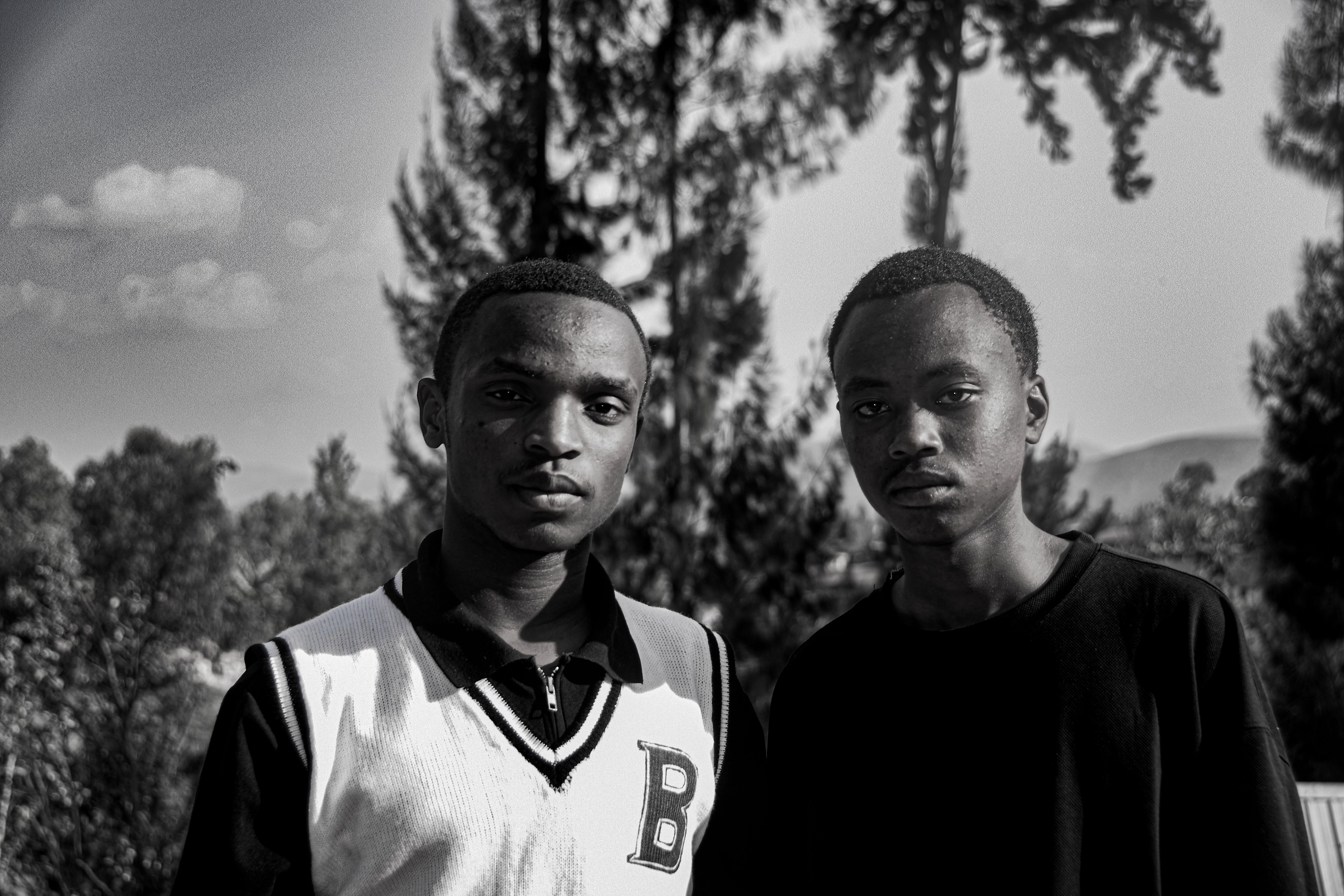 Black and white portrait of two young men in Western Province, Rwanda outdoors.