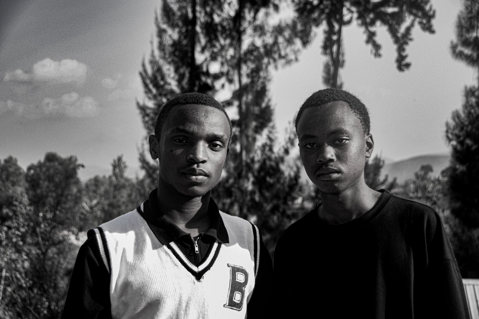 Black and white portrait of two young men in Western Province, Rwanda outdoors.