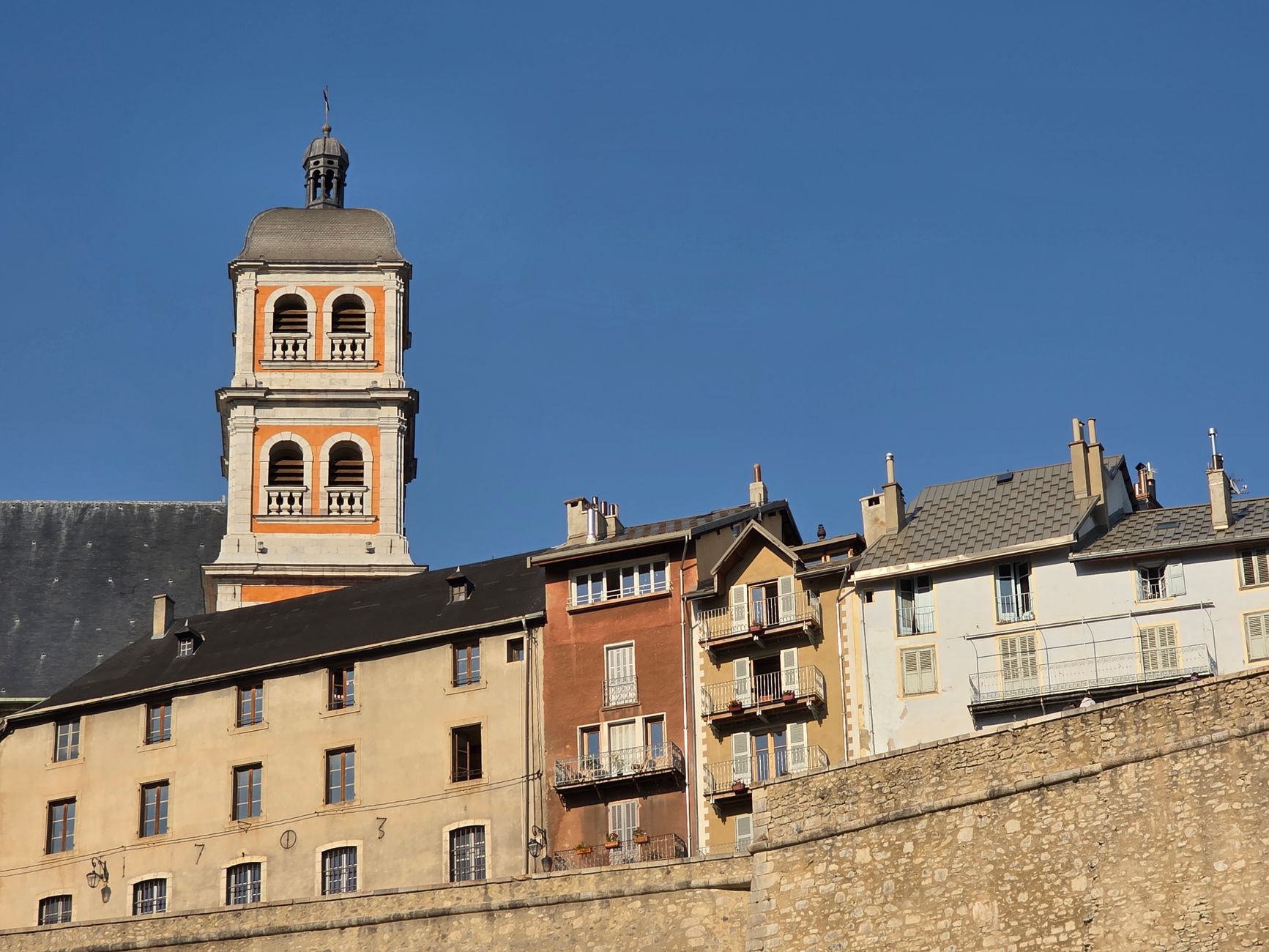 Historic Chambery Cathedral bell tower among traditional buildings under a clear sky.