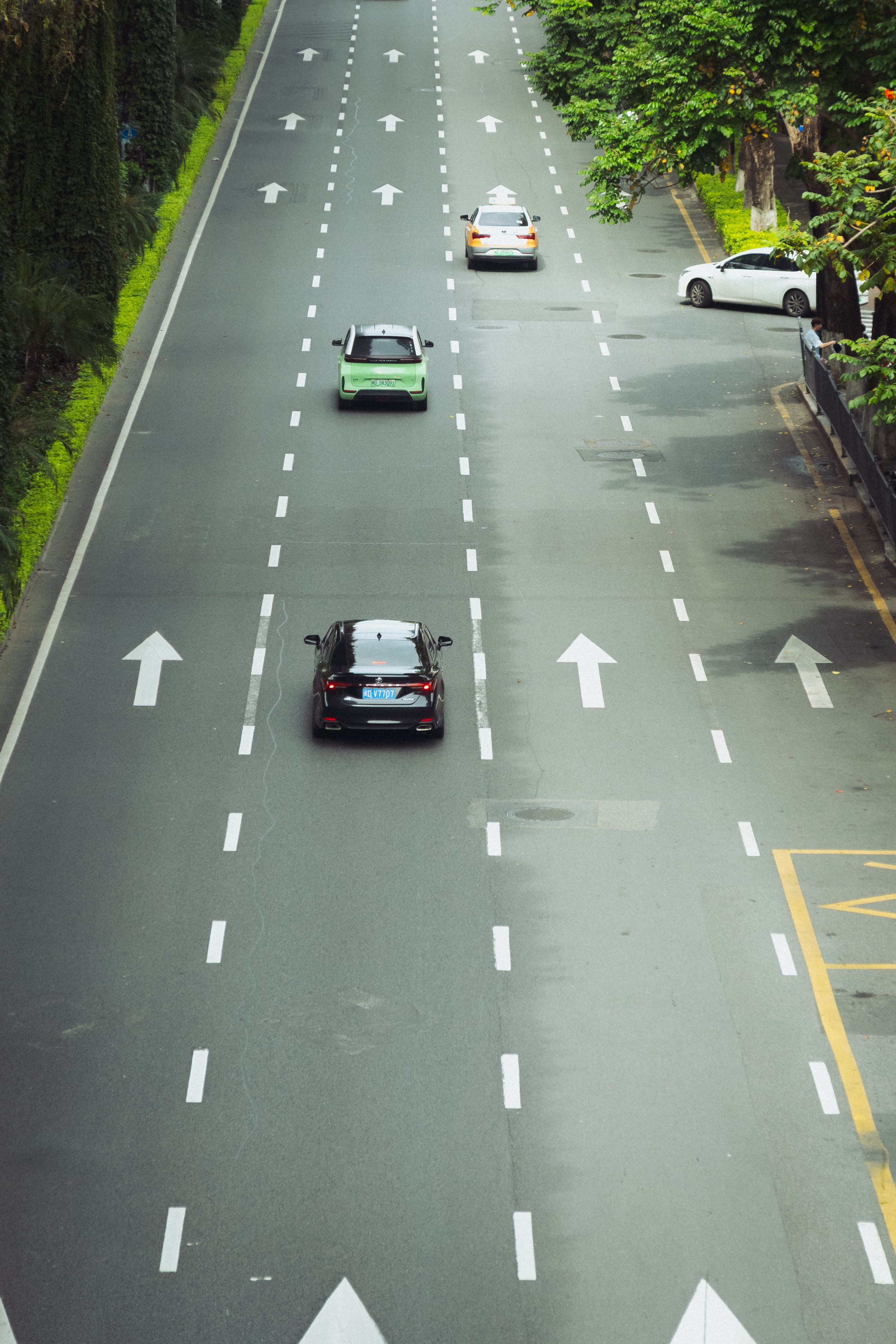 High-angle shot of a four-lane road with cars and clear traffic lines.