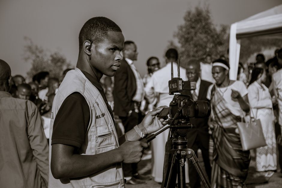 Fotomural Un fotógrafo documenta un animado evento al aire libre en Ruhango, Ruanda. Ambiente cultural vibrante.