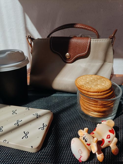 Free Chic setup of a handbag, biscuits, and coffee cup in natural light. Stock Photo