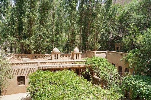 Free Experience the serene beauty of traditional Uyghur architecture nestled in a lush Xinjiang forest. Stock Photo