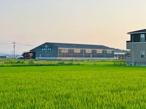 Free Scenic view of a lush green field and warehouse at sunset. Stock Photo