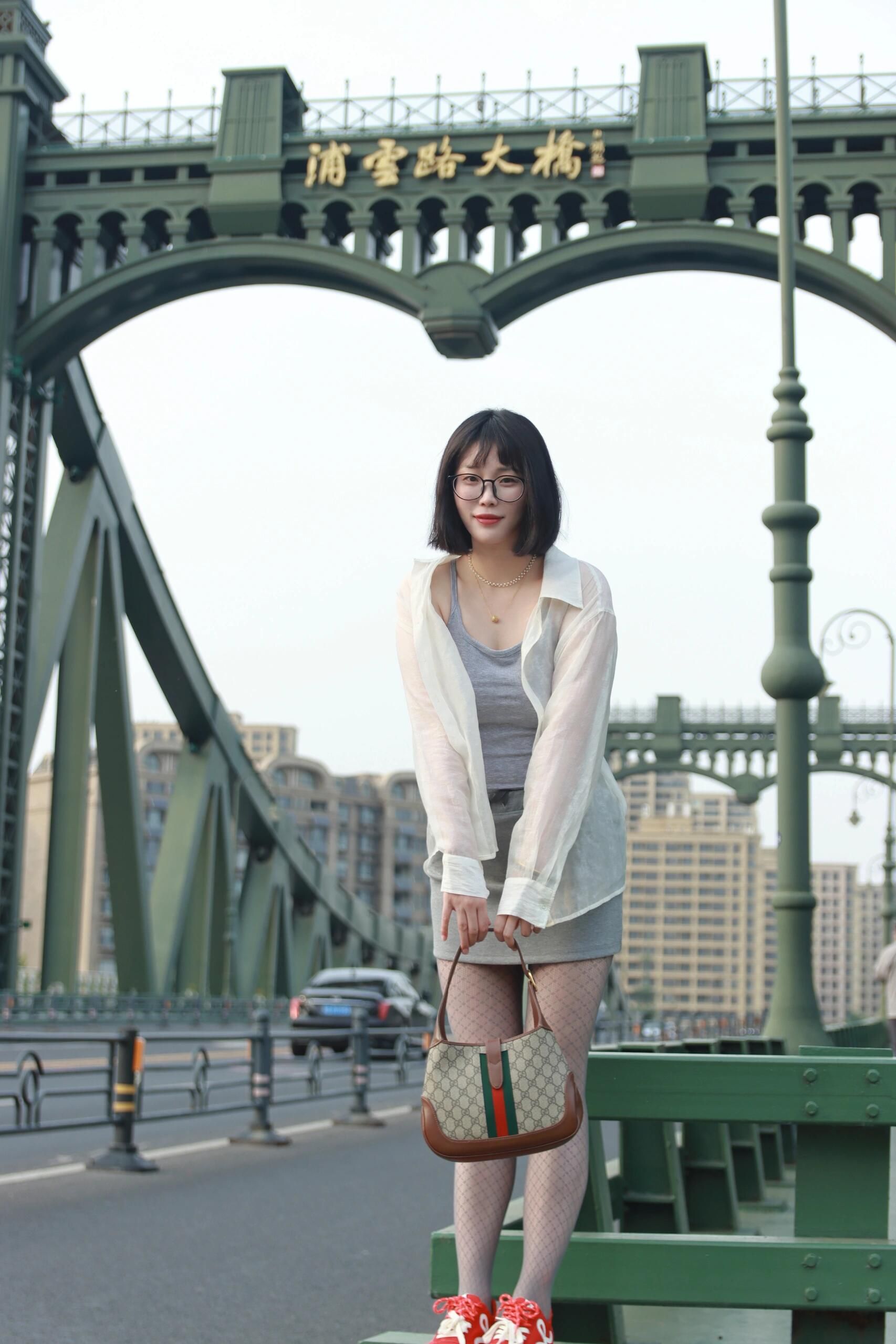 Young woman posing on a bridge in Nanjing, China wearing fashionable attire.