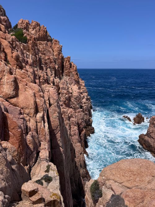 Free Stunning view of Sardinia's rugged cliffs with waves crashing against rocks under a clear blue sky. Stock Photo