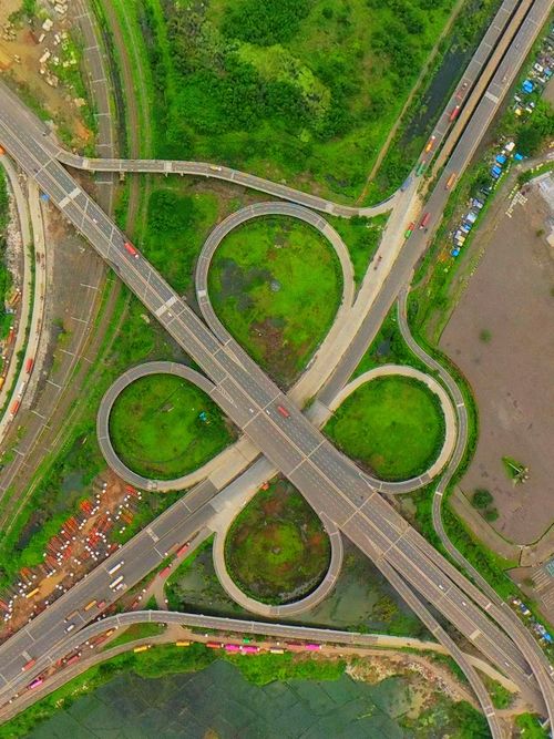 Free Aerial shot of a highway interchange with lush green surroundings, displaying road connectivity. Stock Photo