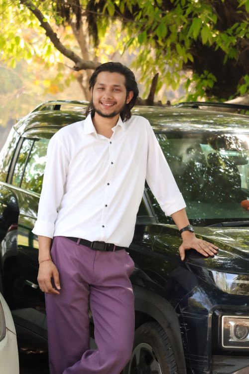 Free Casually dressed young man leaning on a car under trees. Bright and cheerful outdoor scene. Stock Photo