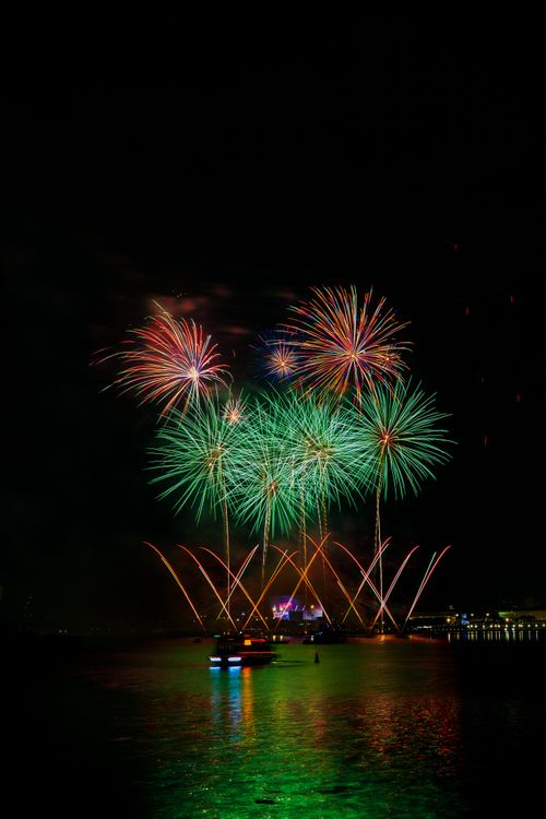 Free A mesmerizing fireworks show exploding in brilliant colors over water during nighttime. Stock Photo