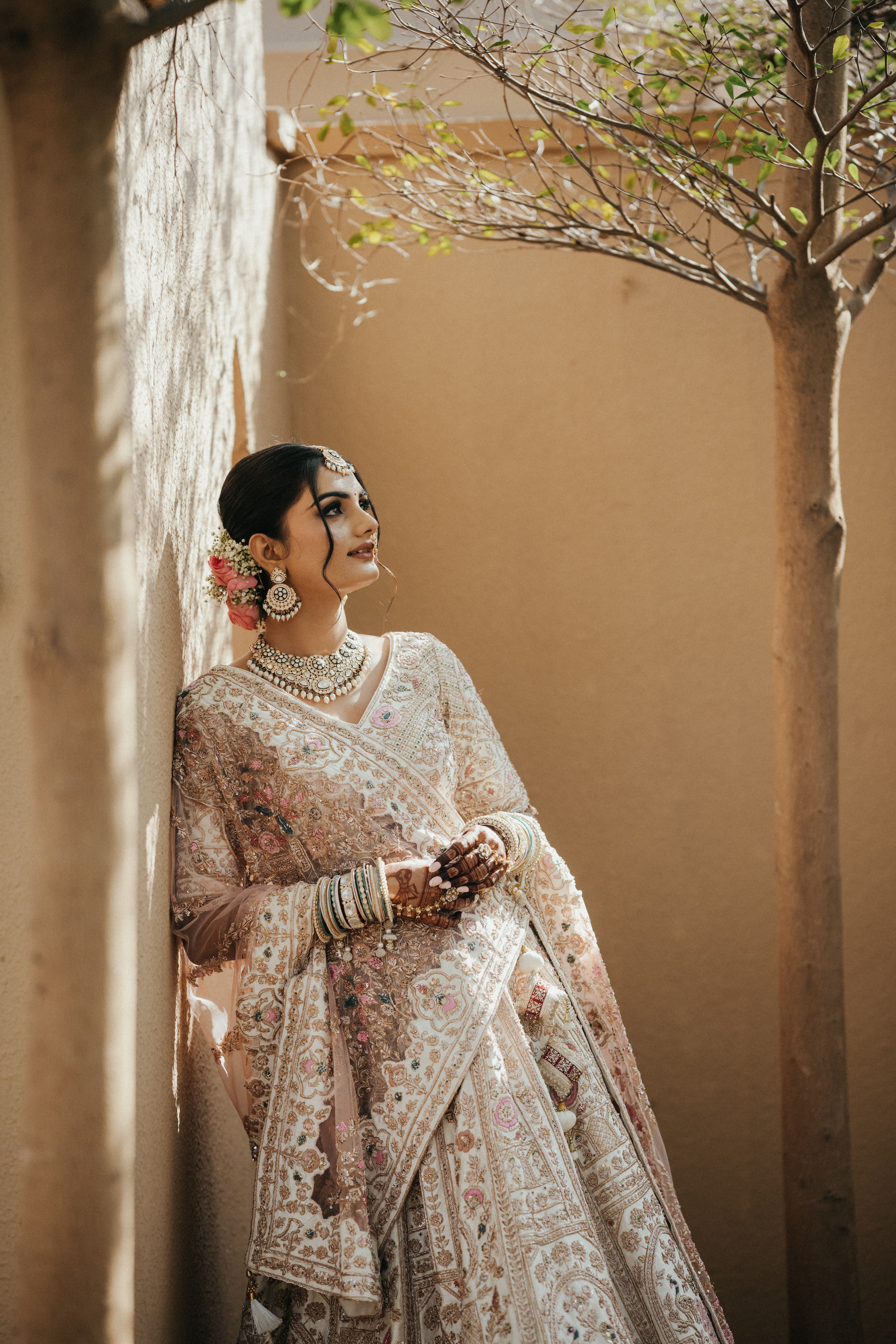 Elegant bride in a traditional Indian saree, adorned with jewelry, standing outdoors.