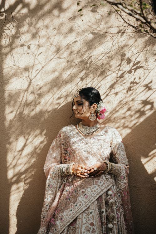 Free A graceful bride in a traditional Indian saree, adorned with jewelry and floral accents, bathed in sunlight and shadows. Stock Photo