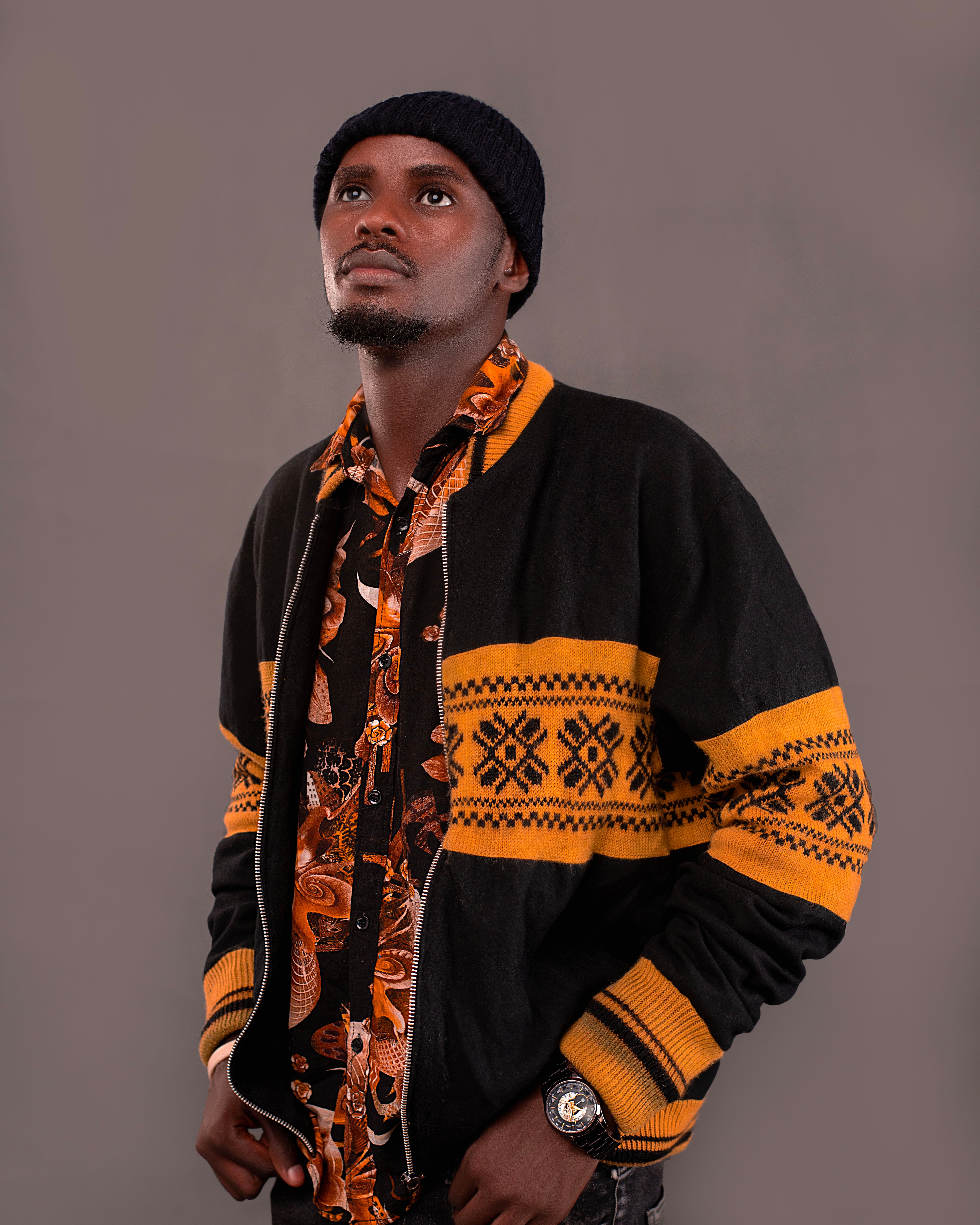 Portrait of a young man wearing traditional African-inspired fashion with a thoughtful upward gaze.
