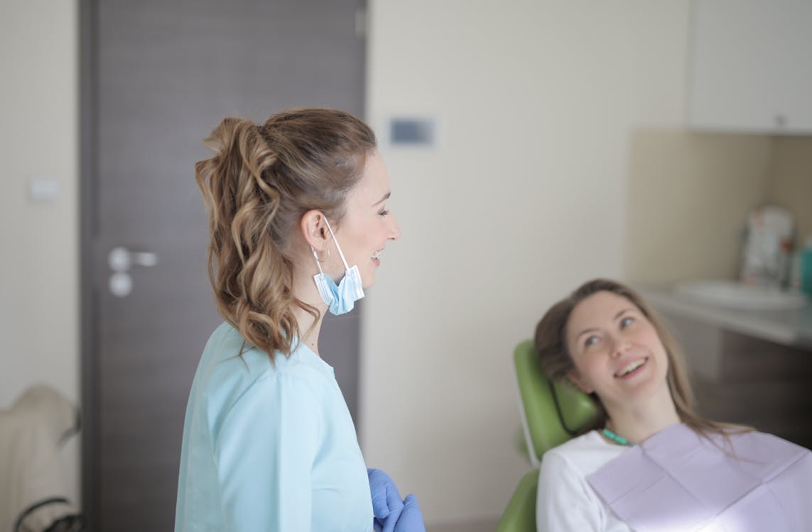 Cheerful young female dentist talking with patient in modern clinic