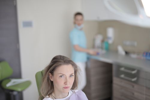 Free From above serious young female patient sitting in dental chair while preparing for medical treatment in modern clinic and looking at camera Stock Photo