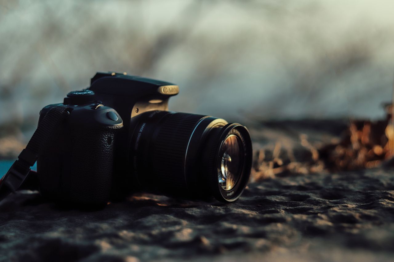 close up of a dslr camera on a rocky surface capturing soft golden sun