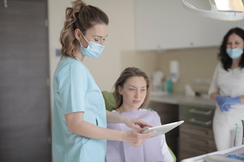 Free Young female dentist using tablet during treatment in clinic Stock Photo