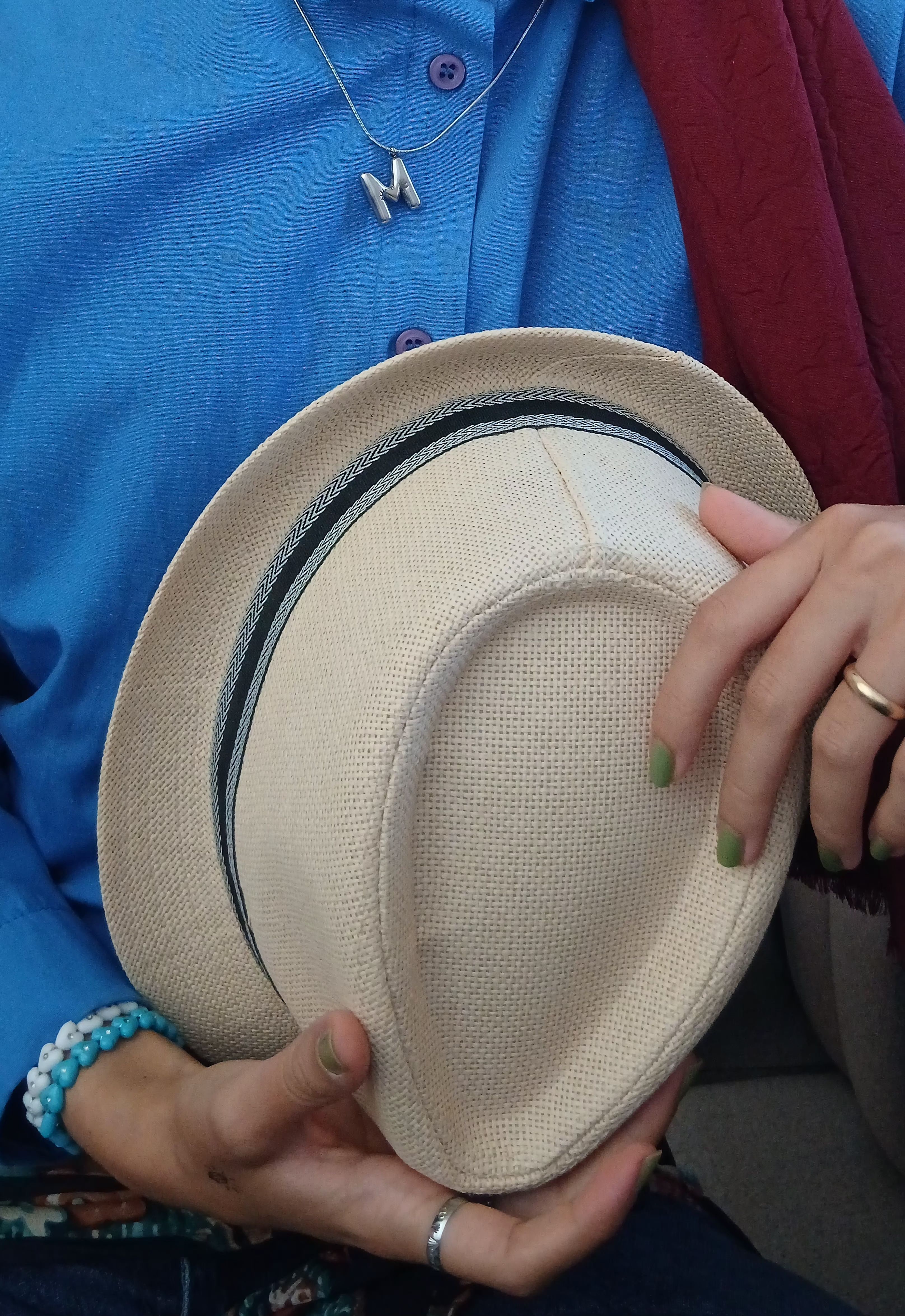 Close-up of person holding straw hat, colorful attire, modern style.