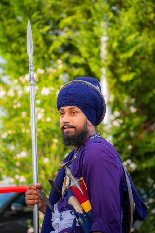 Free A Sikh man in blue traditional attire holding a spear, standing outdoors. Stock Photo