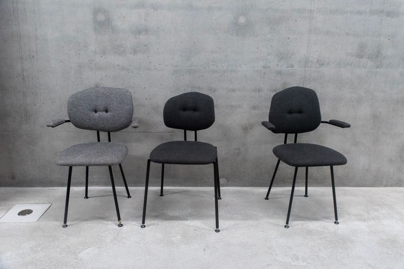 Three modern chairs arranged against a gray concrete wall, ideal for office or interior design themes.