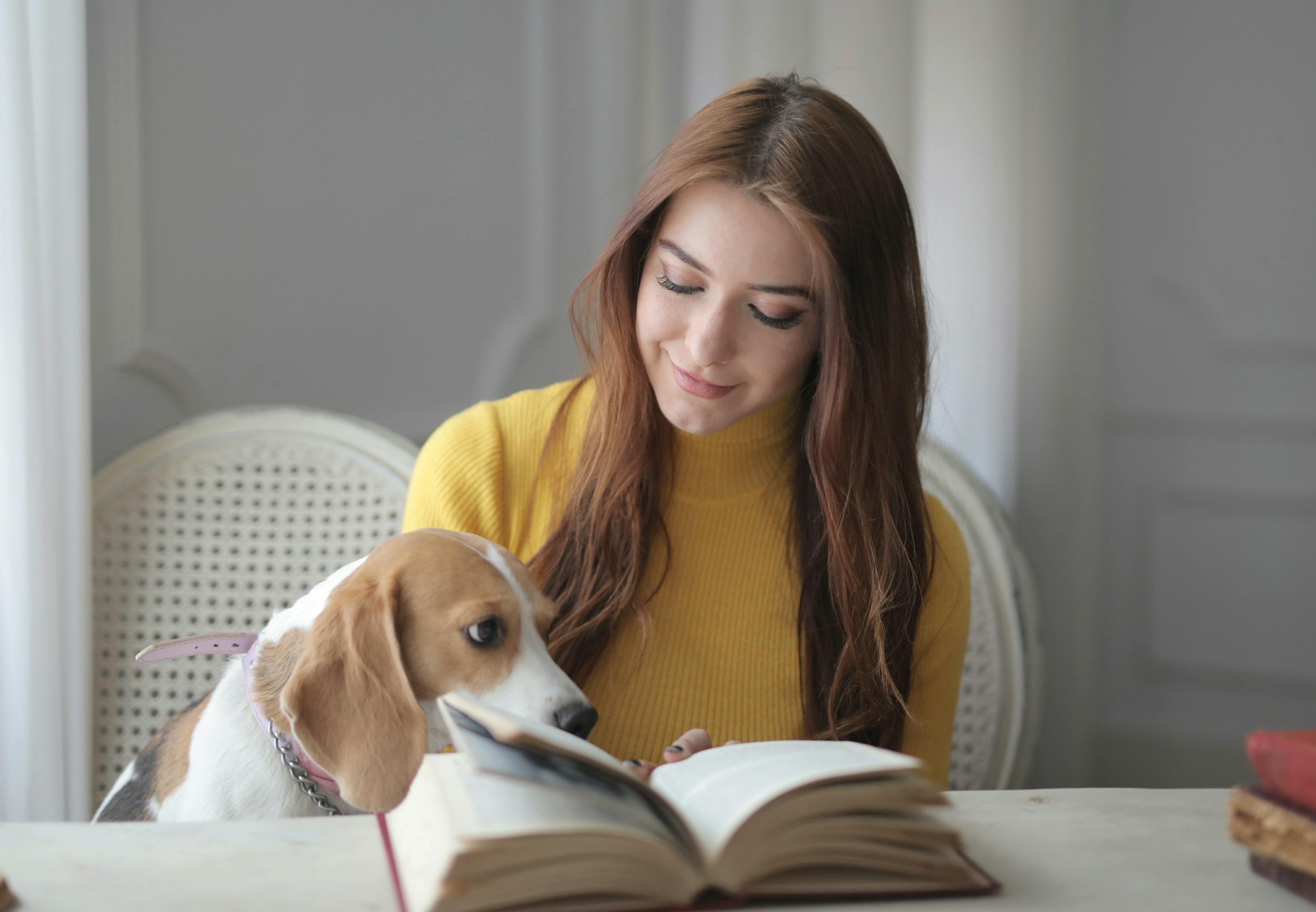 Happy woman in casual clothes with cute dog reading book