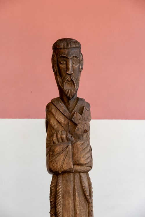Free A detailed wooden sculpture stands against a soft pink backdrop, showcasing craftsmanship. Stock Photo